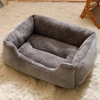 Panier rectangulaire gris vu de trois quarts, avec intérieur en peluche et rebord avant abaissé, sur un tapis clair.